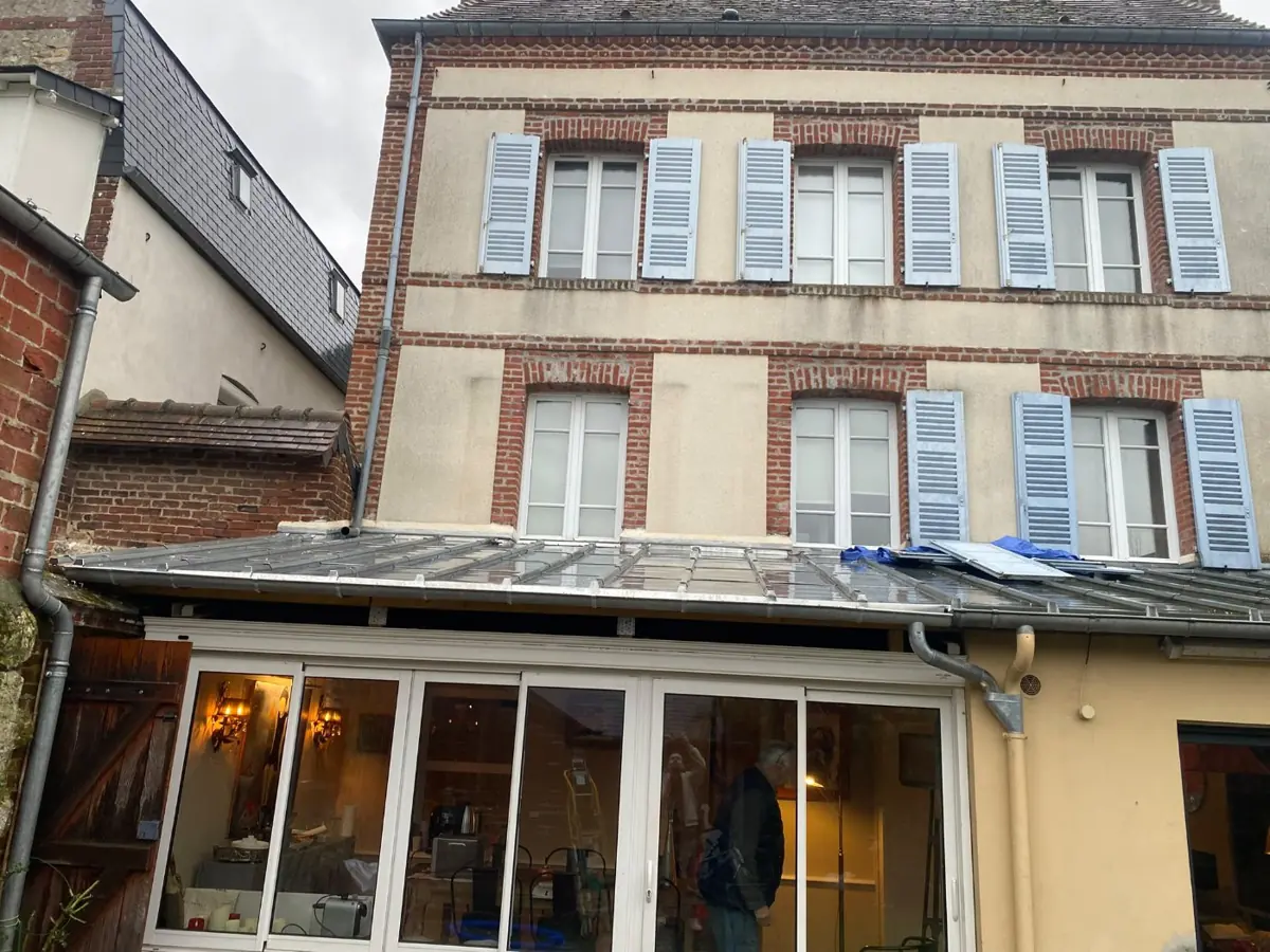 Façade en briques avec véranda et volets bleus