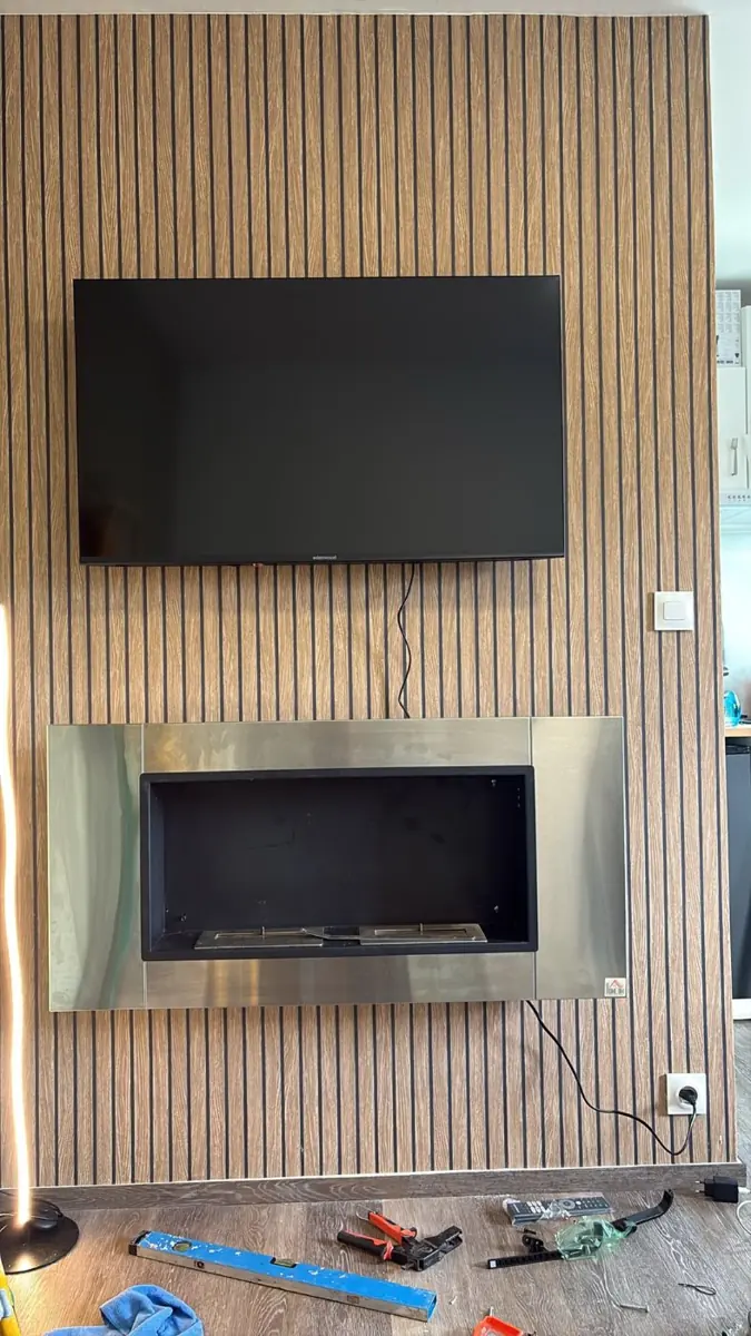 Mur habillé de tasseaux de bois avec téléviseur et cheminée