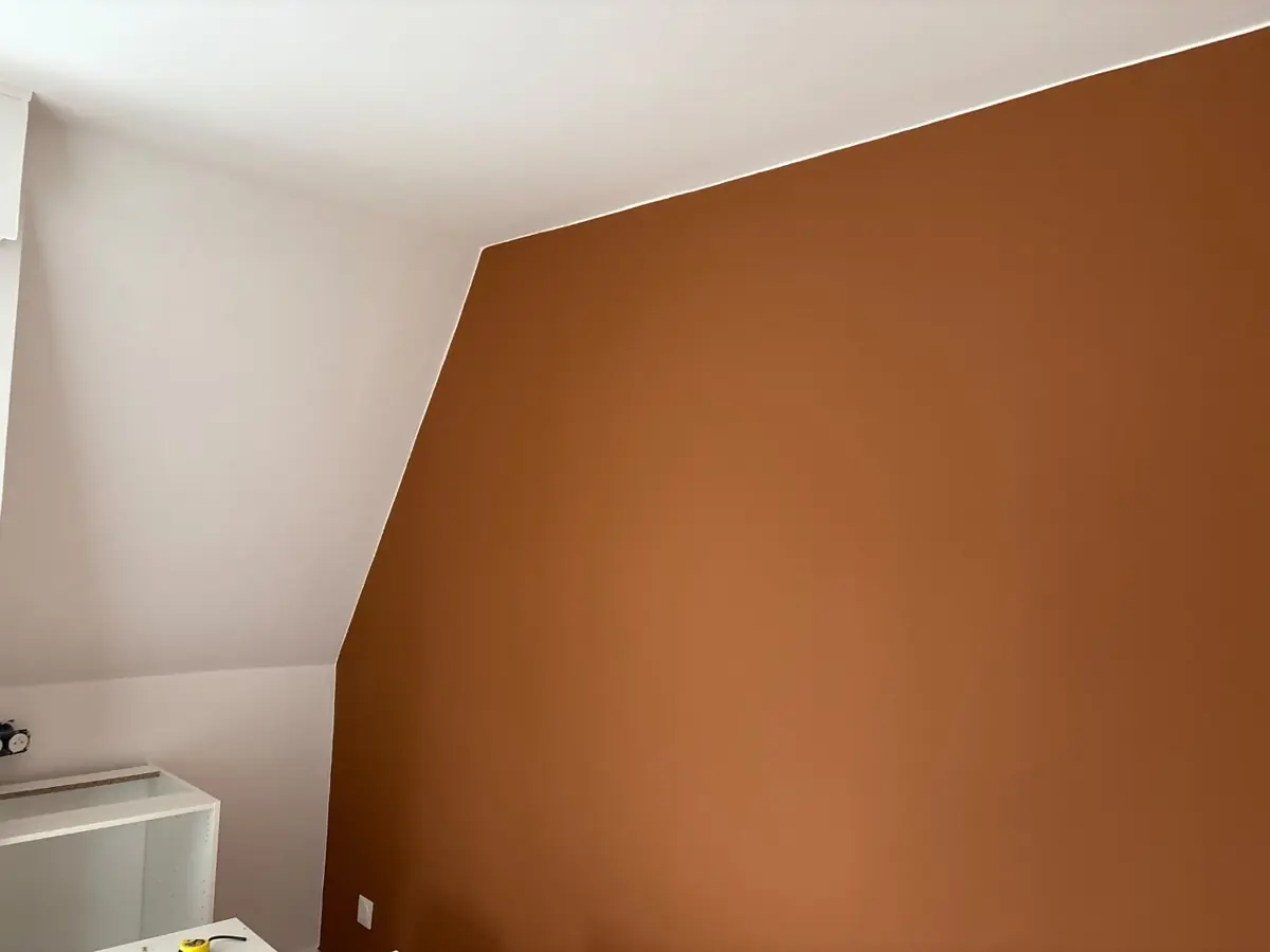 Mur peint en terracotta sous un plafond blanc mansardé