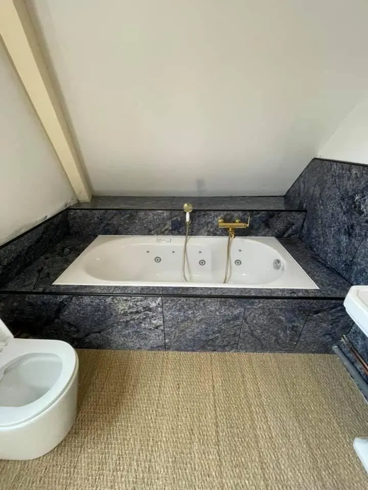 Salle de bain avec baignoire encastrée et murs en pierre sombre