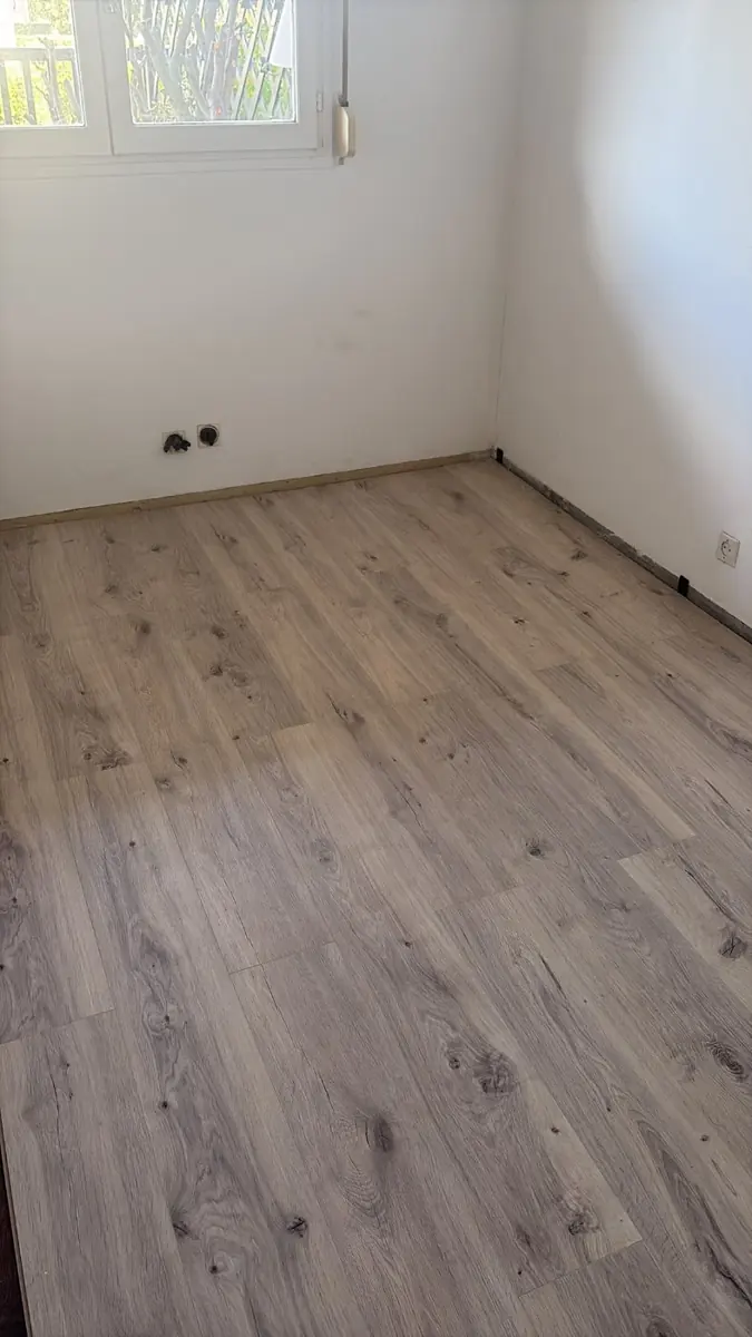 Pièce vide avec sol imitation bois et murs blancs
