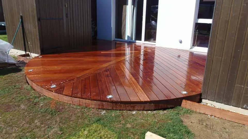 Terrasse en bois de forme arrondie devant une baie vitrée