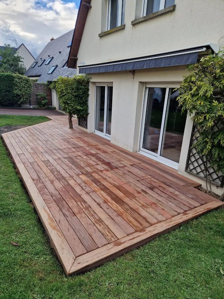 Terrasse en bois en forme de L dans un jardin devant une maison