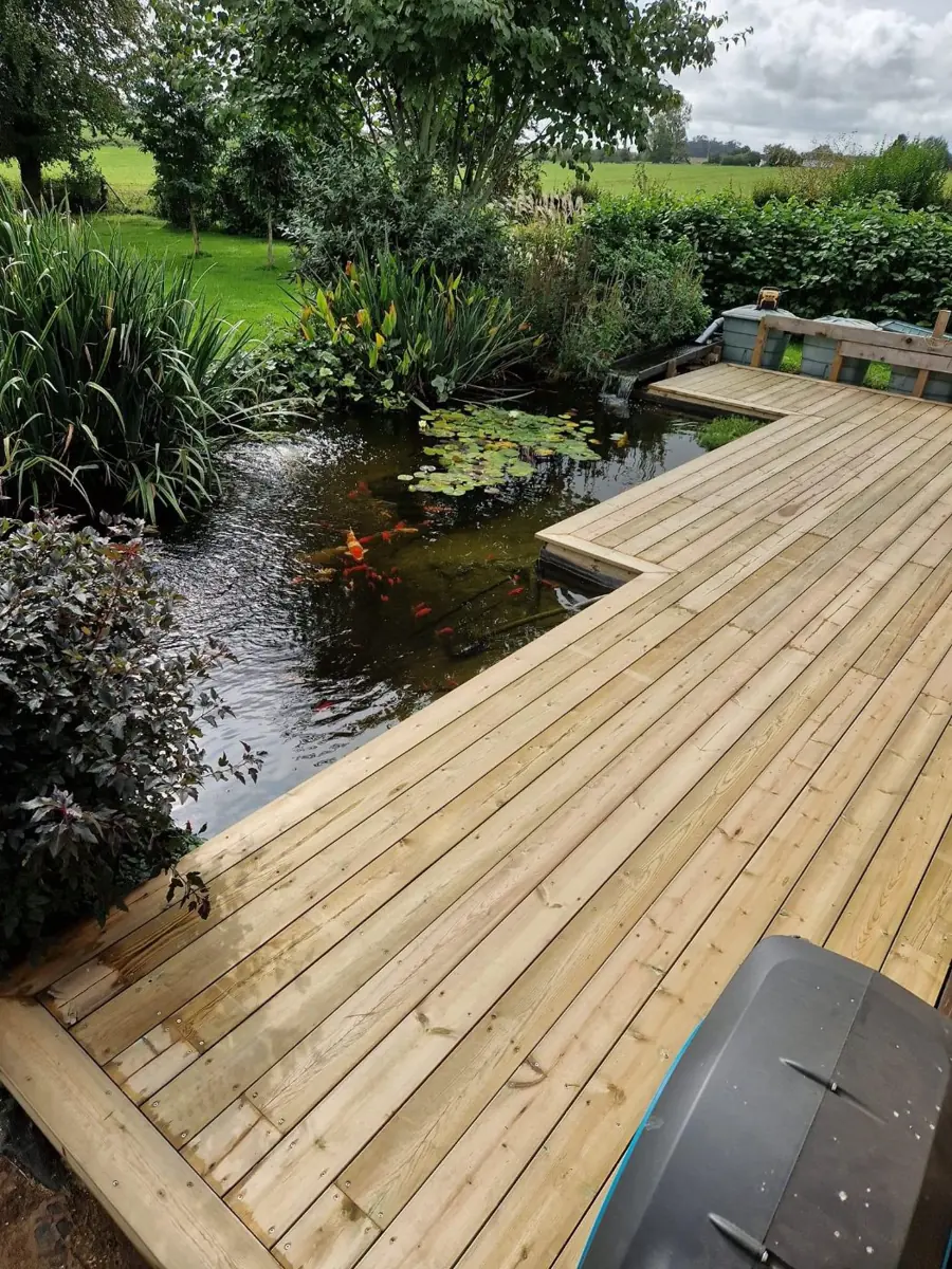Terrasse en bois posée au-dessus d'un bassin dans un jardin