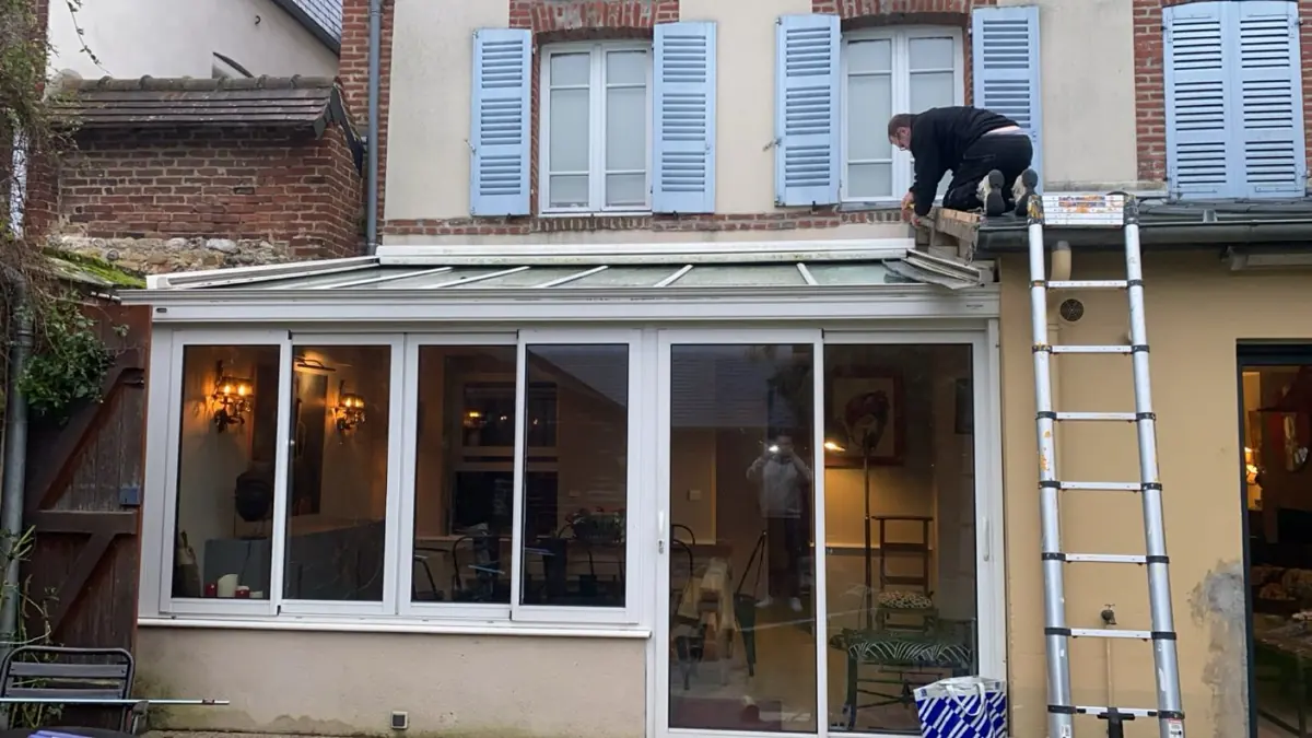 Intervention sur la toiture d'une véranda avec échelle